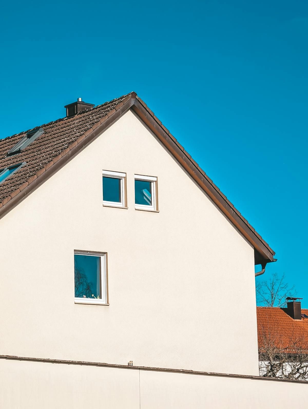 Giebelseite eines weiß verputzten Einfamilienhauses mit Ziegeldach